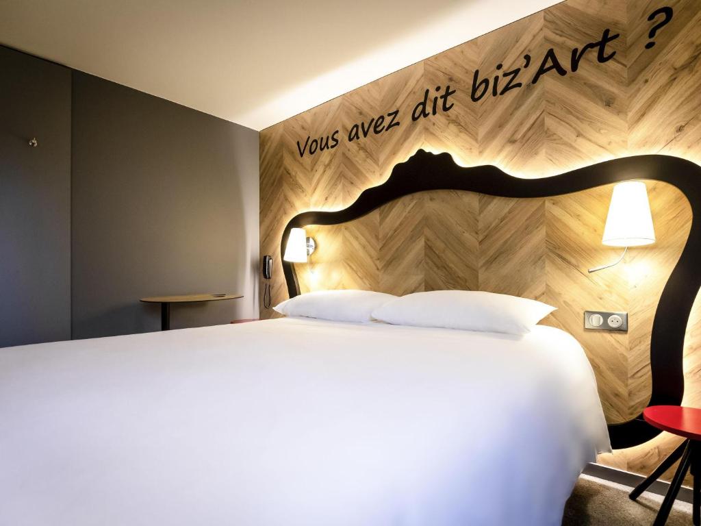 a bedroom with a large bed with a wooden headboard at ibis Styles Douai Gare Gayant Expo in Douai