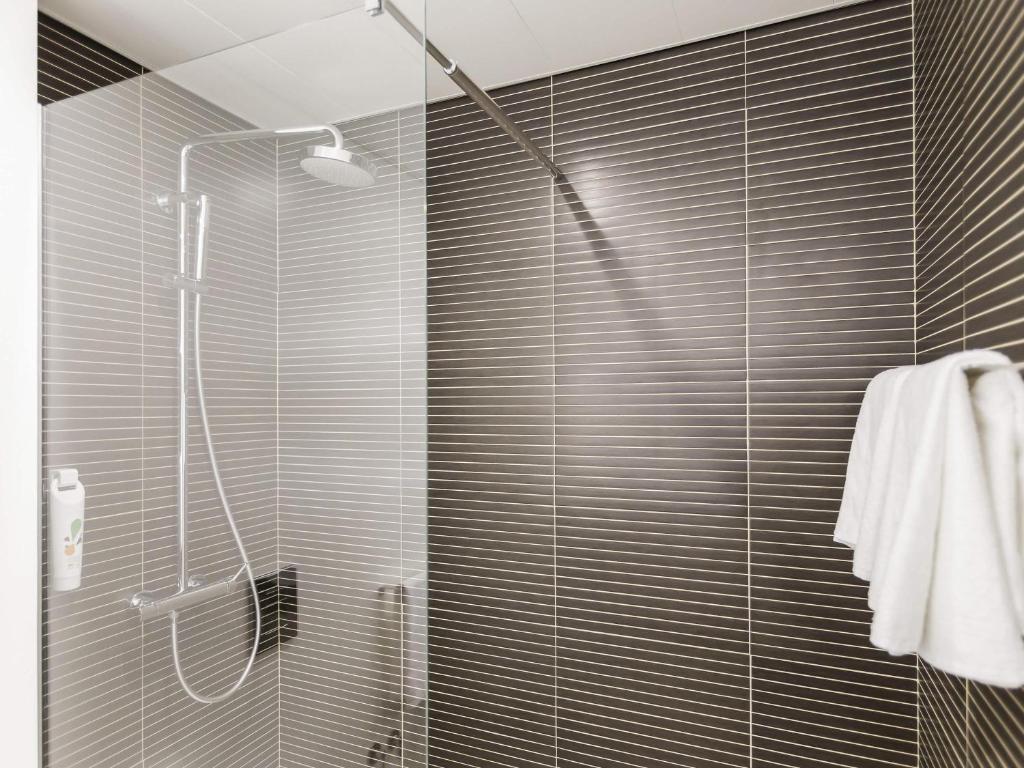 A compact walk-in shower with a clear glass door and dark horizontal wall tiles.