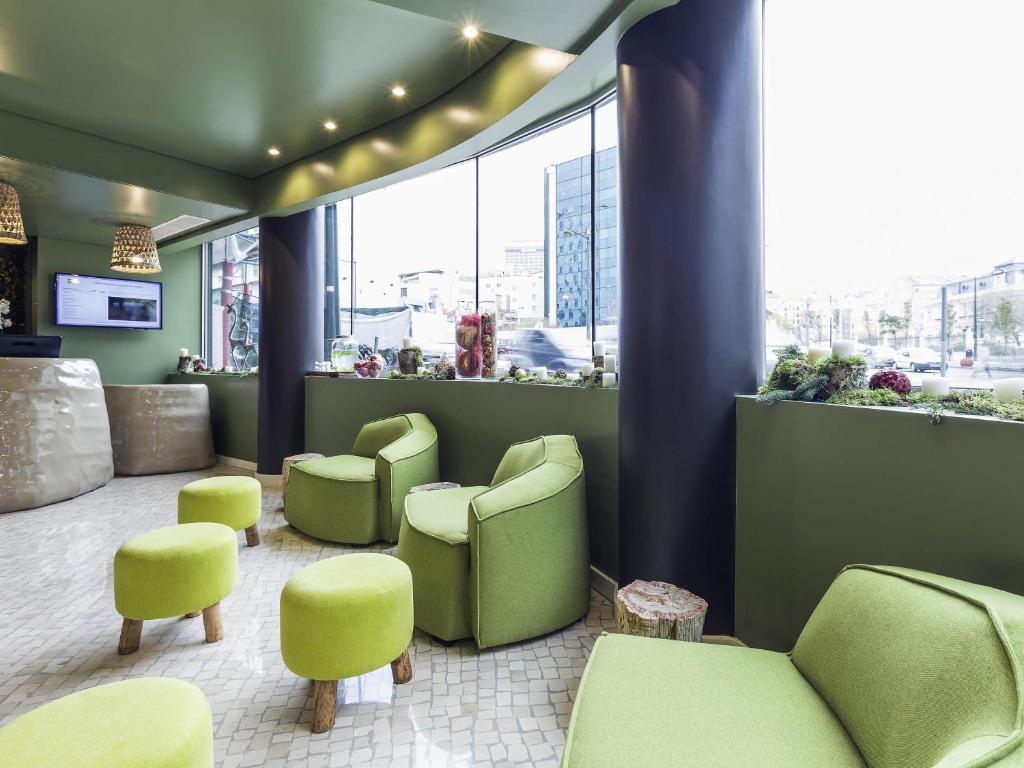 A bright lobby lounge offers lime-green armchairs and stools beside large windows.