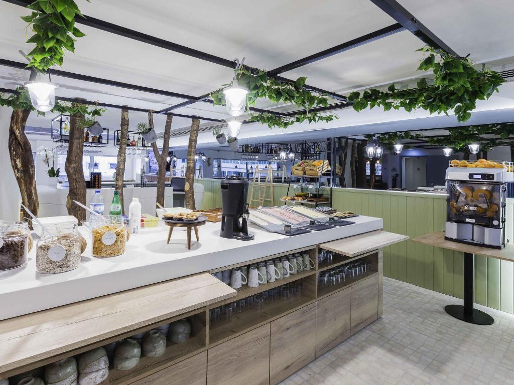 A self-service breakfast counter with cereals, drinks, coffee equipment, and display food.