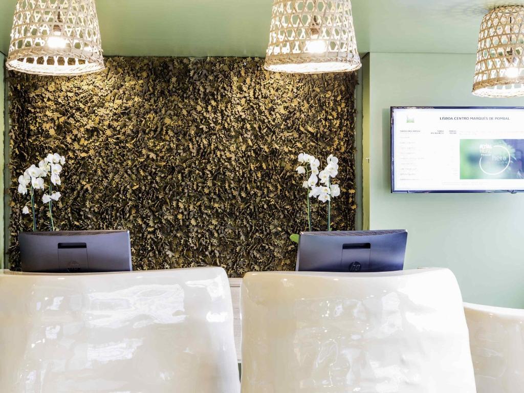 A brightly styled meeting area with two computer stations, pendant lights, and a floral feature wall.