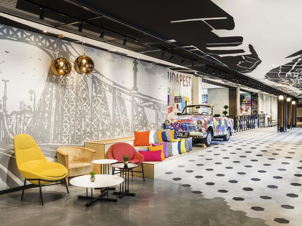 un magasin avec des chaises et des tables et une voiture sur le mur dans l'établissement ibis Budapest Castle Hill, à Budapest