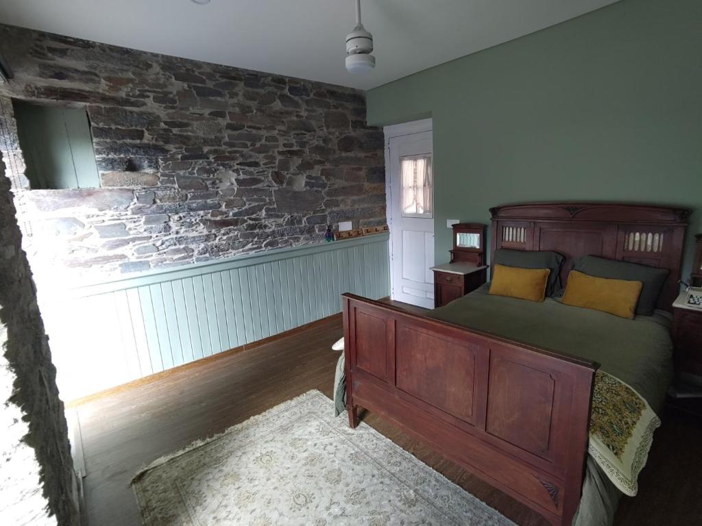 een slaapkamer met een bed en een bakstenen muur bij Refúgio no Douro 