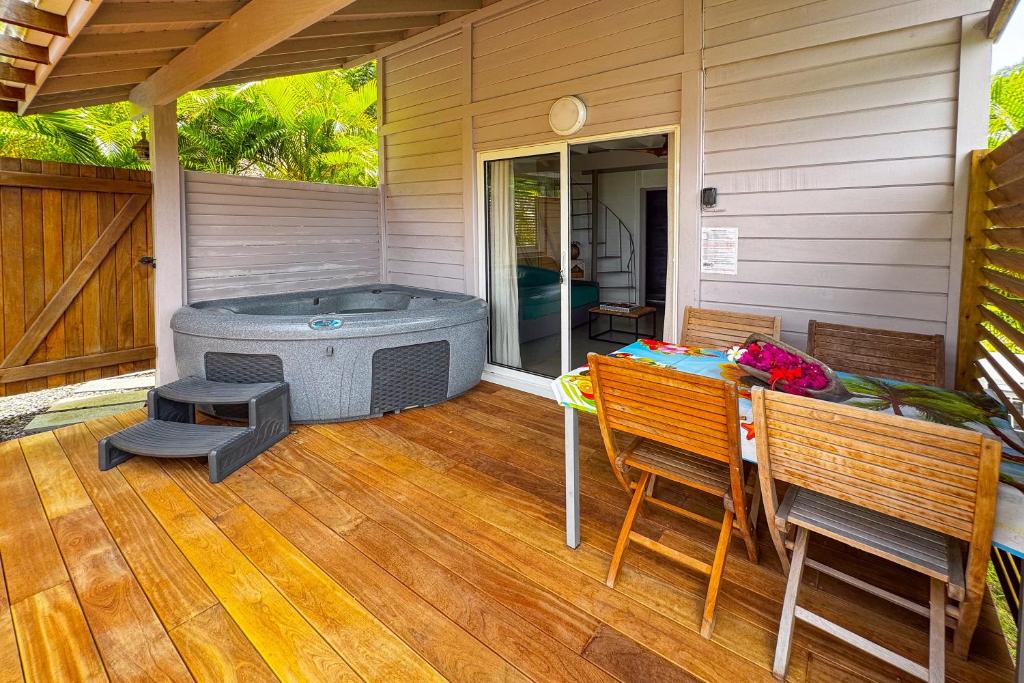 a patio with a hot tub and a table and chairs at Lodge 2 - Hibiscus - Jaccuzi Privé in La Plaine