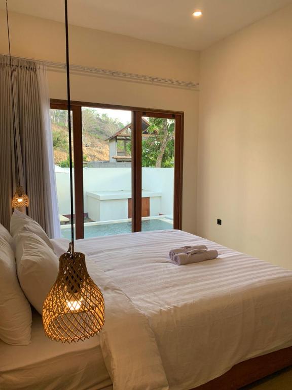 a bedroom with a bed and a large window at Permata Villas Lombok in Kuta Lombok
