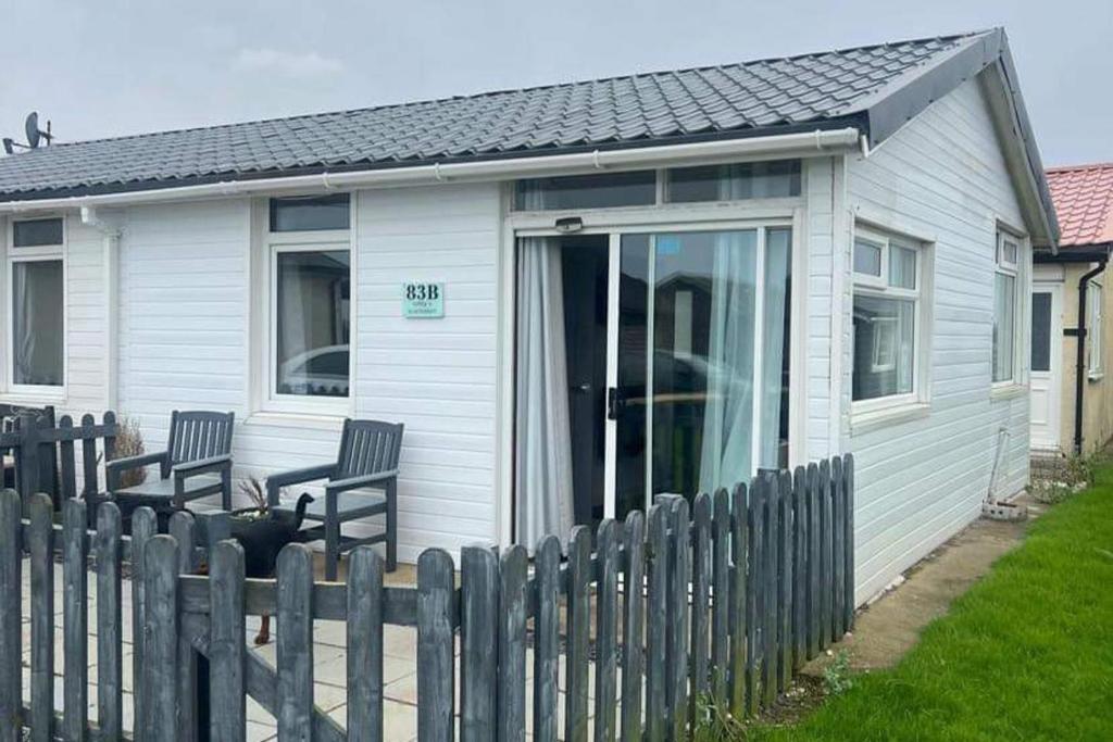 ein weißes Haus mit zwei Stühlen und einem Zaun in der Unterkunft Stunning One Bed Modern & Contemporary Chalet in Bridlington