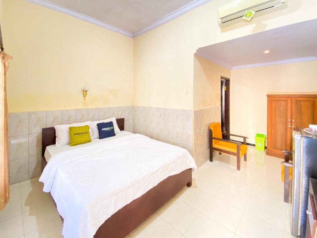 a bedroom with a bed and a chair in it at Surya Guest House Urbanview Probolinggo in Kanigaran