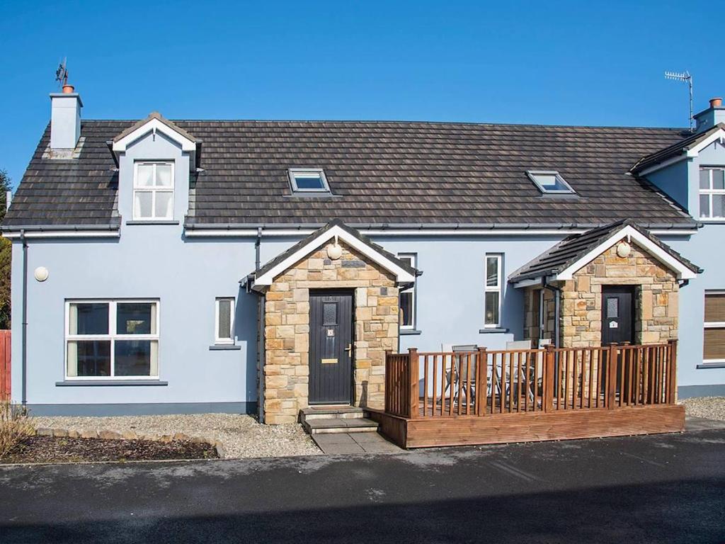 a white house with a wooden fence in front of it at 4 Bed in Portnoo oc-ii16953 in Clogher