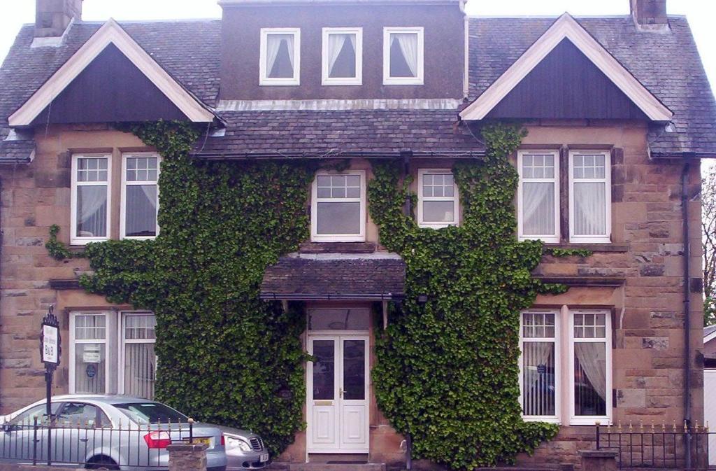 una casa ricoperta di edera con un'auto parcheggiata di fronte di The Old Tramhouse Self Catering Apartments a Stirling