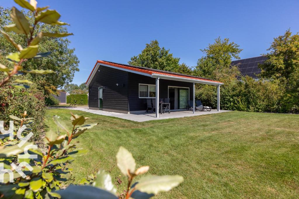 a black house with a red roof and a yard at Gezellige vakantiewonig gelegen in Grijpskerke in Grijpskerke
