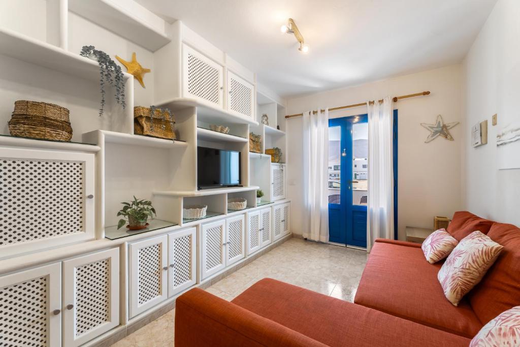 カレタ・デ・ファマラにあるFamara Power Apartmentのリビングルーム(赤いソファ、青いドア付)