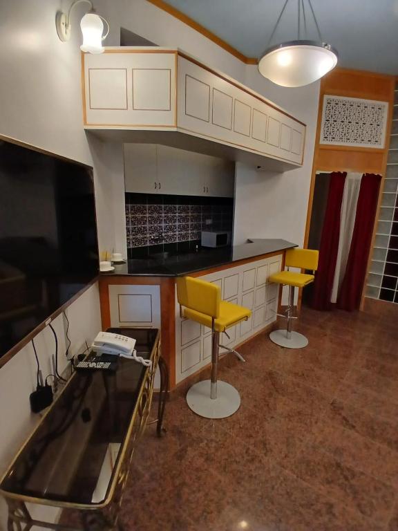 cocina con encimera y 2 sillas amarillas en Qurum Heights Hotel, en Mascate