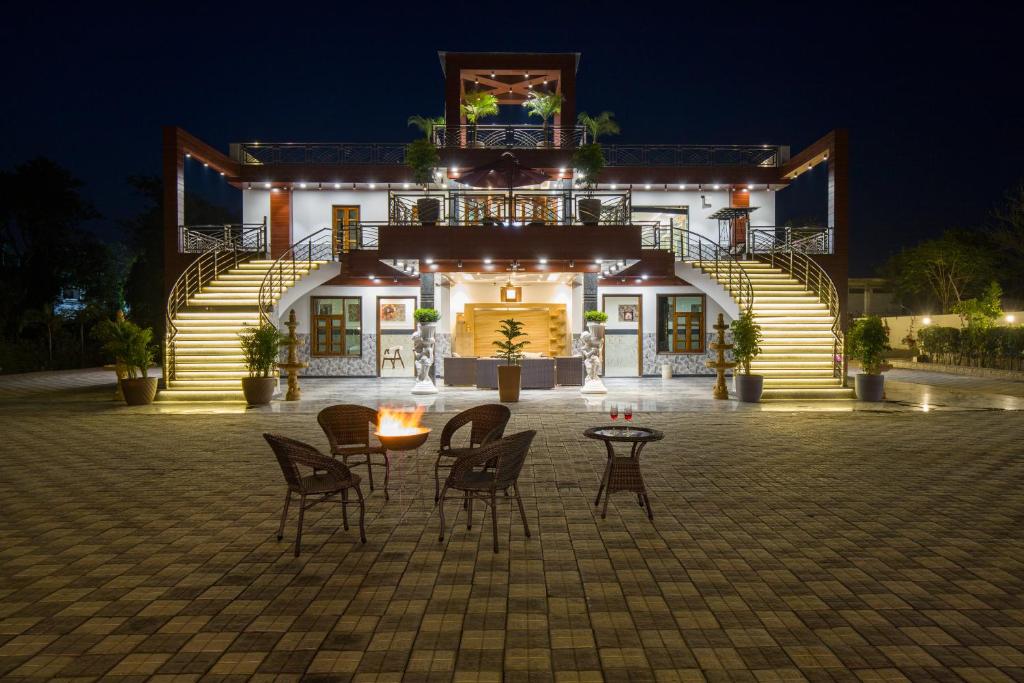 a building with chairs and a table in front of it at ELIVAAS Ivory estate 5 BHK Farm with Pvt Pool, Gazebos & Lounge Area in Manjhāoli