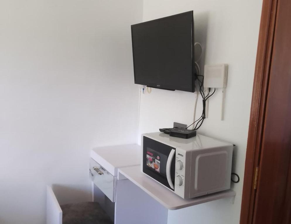 une télévision au-dessus d'un micro-ondes sur une étagère dans l'établissement Acacia Sky, à Nakuru