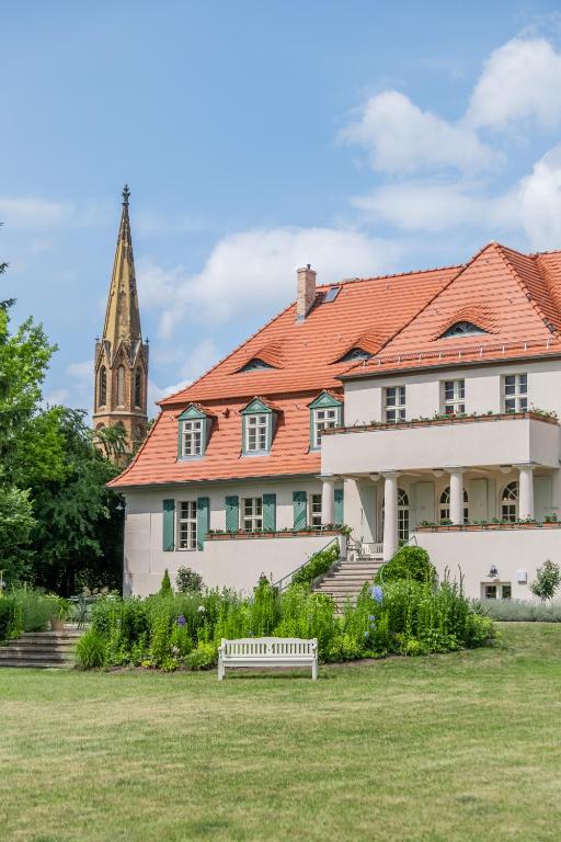 a building with a red roof and a church at Gutshaus Lietzow in Nauen