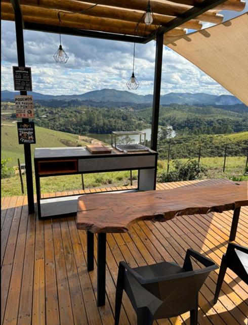 a wooden deck with a table and a bench at Domo com vista do Lago e Montanhas in Igaratá