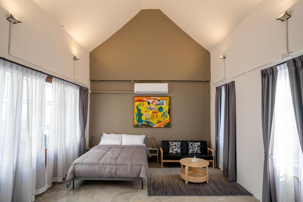 a bedroom with a bed and a chair at Crownex Studio Deluxe in Ban Nong Chaeng