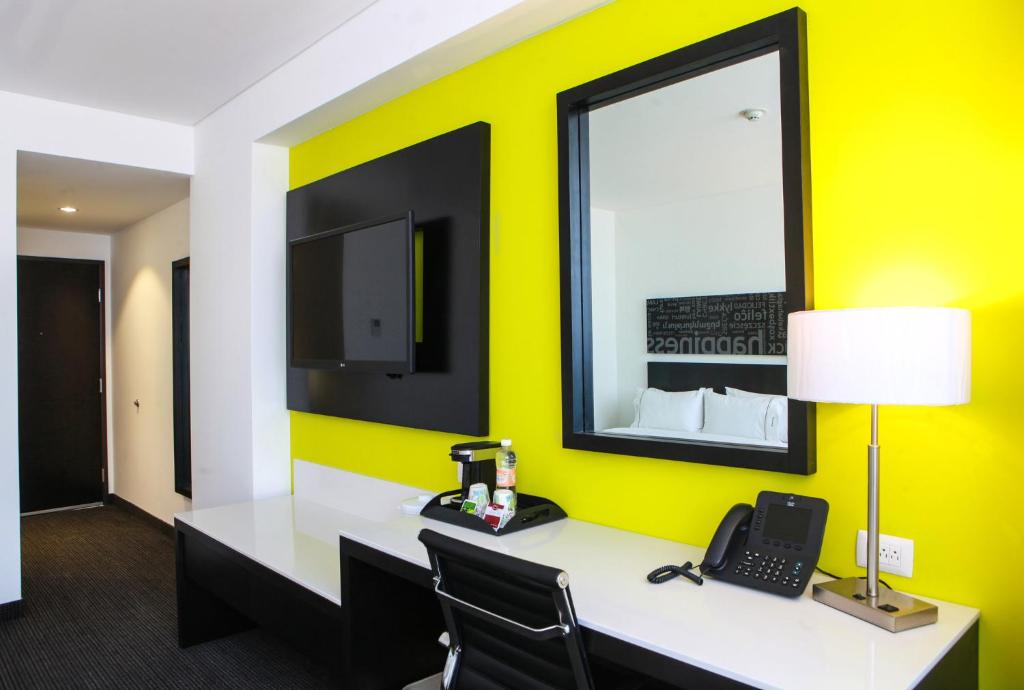Una habitación con un escritorio con teléfono y una pared amarilla. en Holiday Inn Express & Suites Puebla Angelopolis by IHG, en Puebla