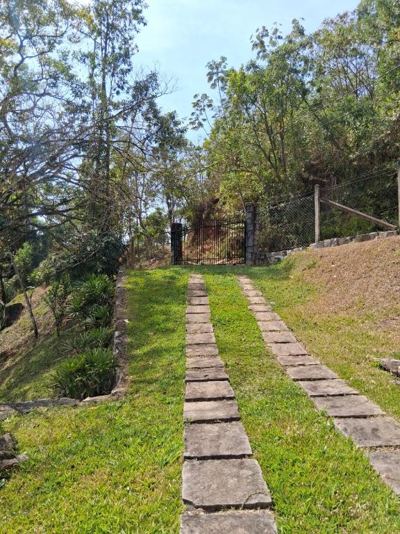 a stone path through a field with a fence at Cottage in Penedo! in Itatiaia