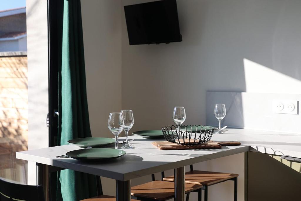 a table with glasses and plates on it in a kitchen at Le Jardin de Sauge in Le Teich