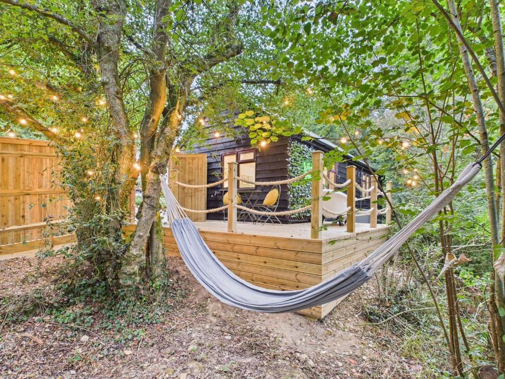 a hammock in front of a tree house at Lake View Lodge & Outdoor Bath in East Grinstead