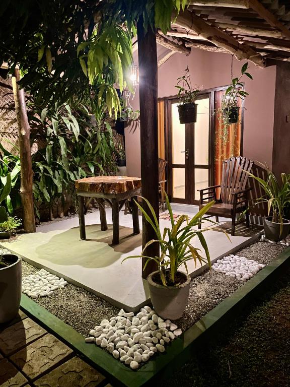 a patio with a table and a bench and plants at Elephant Side Safari Bungalow in Udawalawe