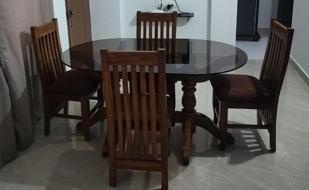 a dining room table with four chairs and a glass top at H M G service apartment in Sringeri