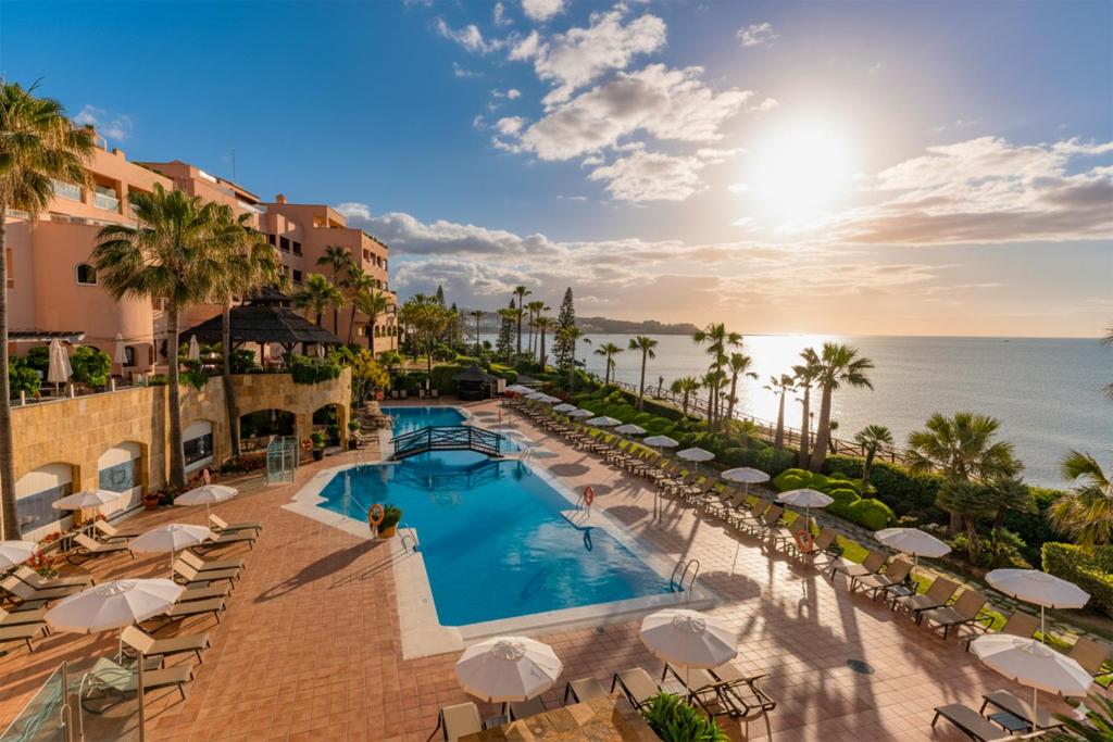 una imagen de una piscina del complejo con sillas y sombrillas en Elba Estepona Gran Hotel &amp; Thalasso Spa, en Estepona