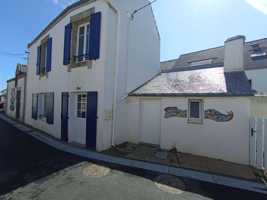 a white building with blue shutters on a street at Maison de charme au centre d'Étel - Idéale pour famille - FR-1-479-234 