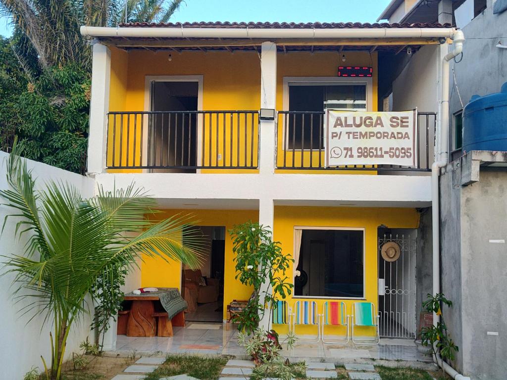 una casa amarilla con un balcón y un cartel en ILHA De ITAPARICA PONTA DE AREIA CASA DA NÉIA TEMPORADA, en Itaparica