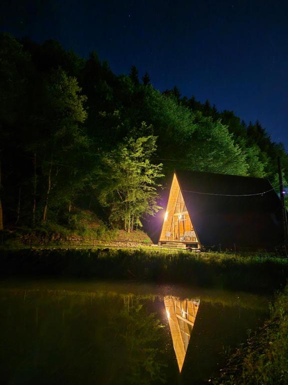 a house is lit up at night next to a lake at Cabana Vatra Râului 