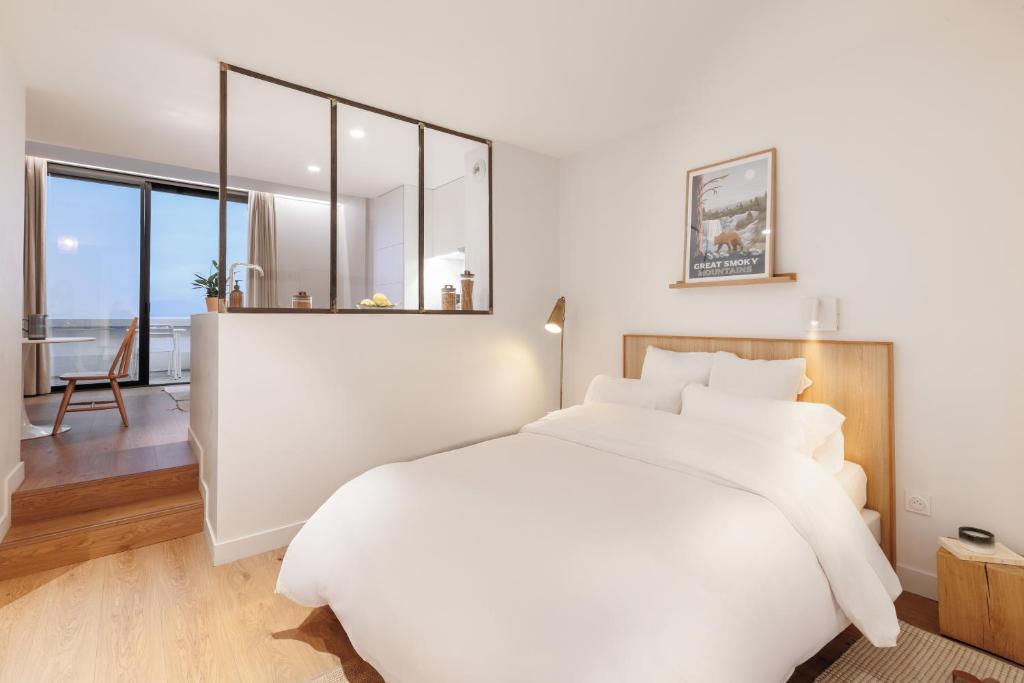 Un dormitorio con una gran cama blanca con un gran espejo. en The Babel Community Hôtel - Grenoble Bastille, en Grenoble