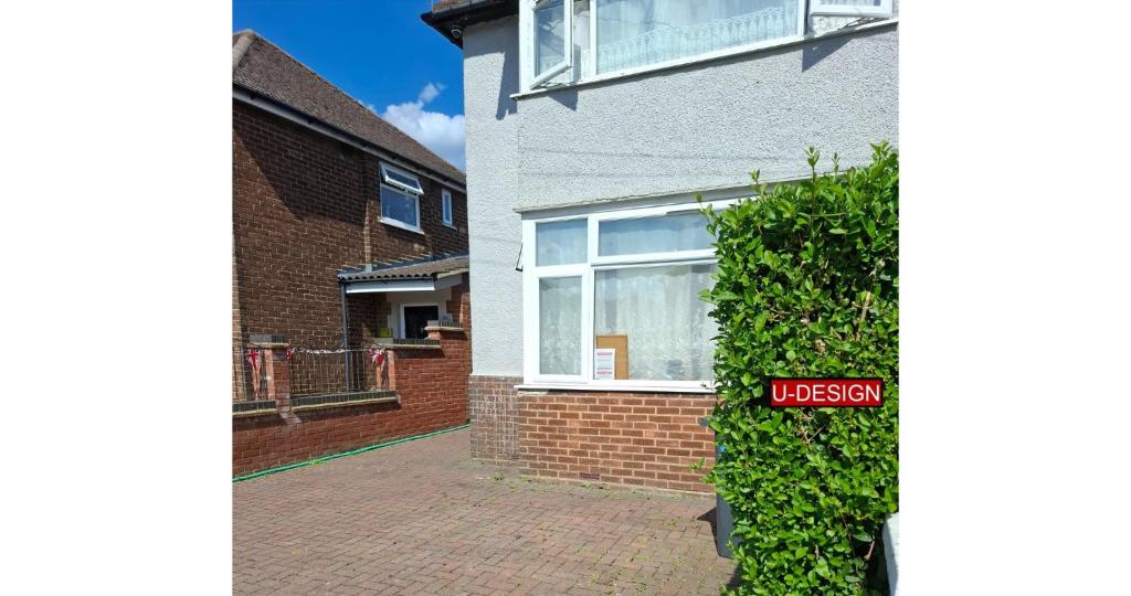 a brick house with a sign in front of a bush at Sundon Park - 1 Bed Flat in Luton