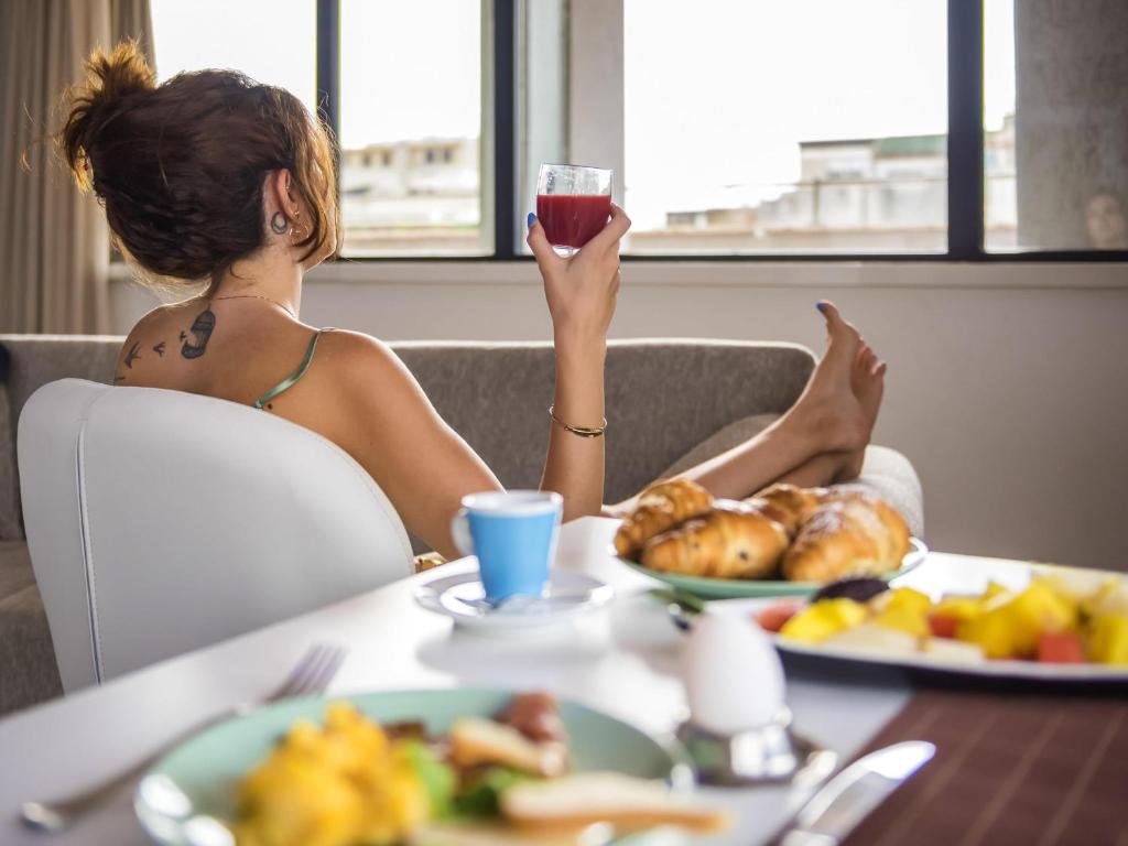 a woman sitting at a table with a glass of wine at Cristal Hotel Palermo in Palermo