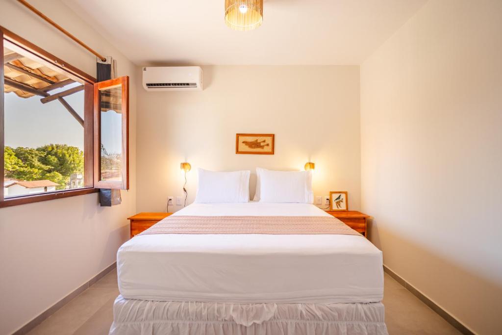 a bedroom with a white bed and a window at Vila Dádiva Jeri in Jericoacoara