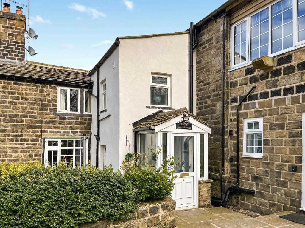an old brick house with a white door at Bank Top Cottage - Uk49215 in Wilsden