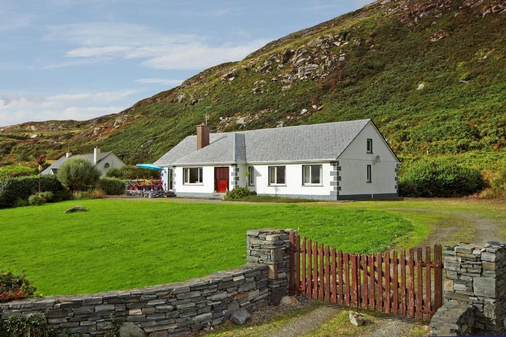 a white house with a fence in front of a hill at 4 Bed in Clifden oc-i243 in Belleek