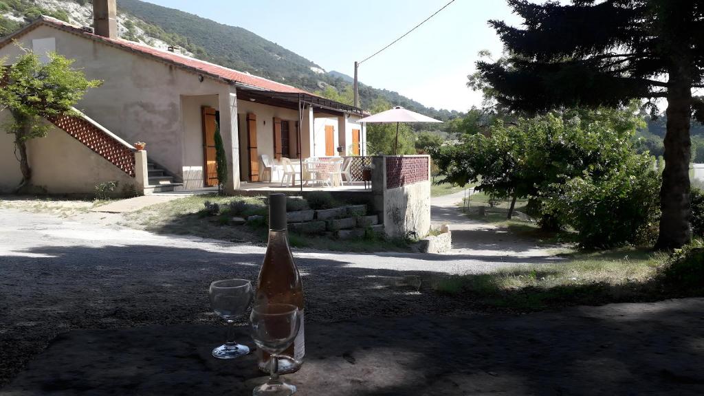 une bouteille de vin et deux verres assis devant une maison dans l'établissement Gîte La Motette Drôme Provençale, à Rousset-les-Vignes