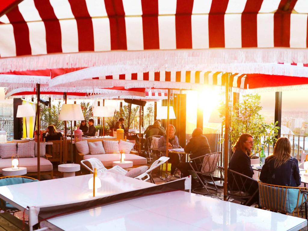 a restaurant with people sitting at tables and umbrellas at Mama Shelter Paris West in Paris