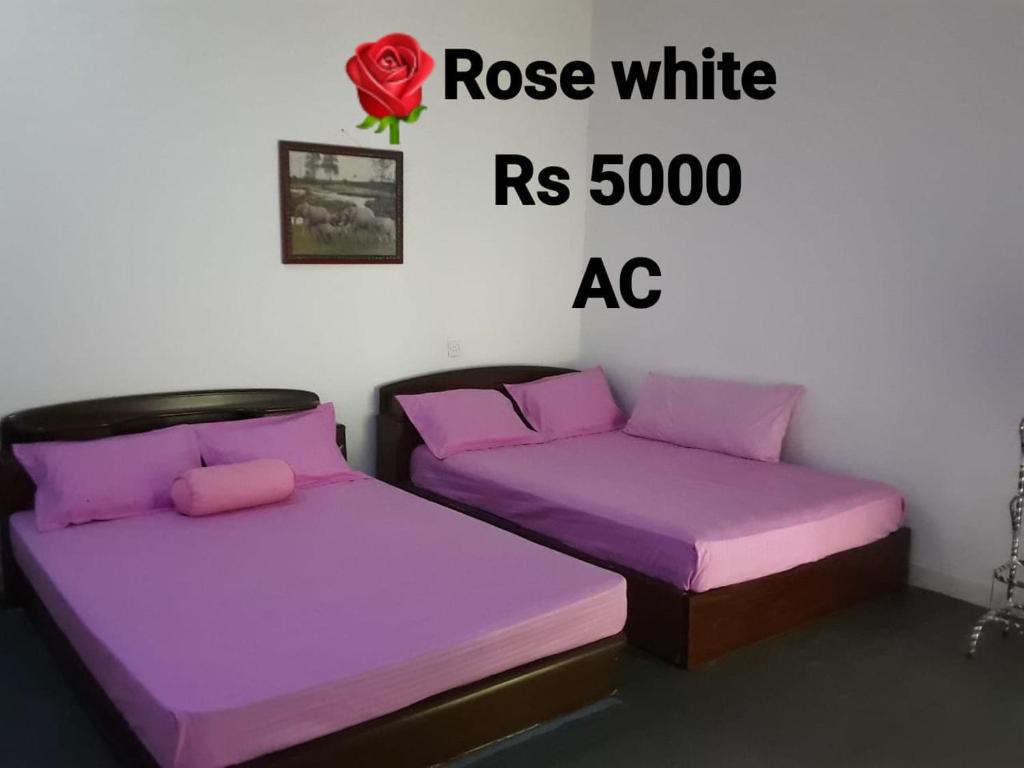 two beds in a room with a rose white ac at Solamba Ella Mountain Resort in Bulatkohupitiya