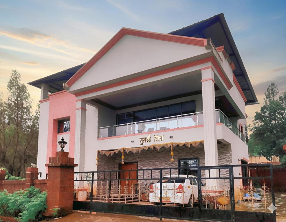 a pink and white house with a balcony at Tulsi Villa in Panchgani