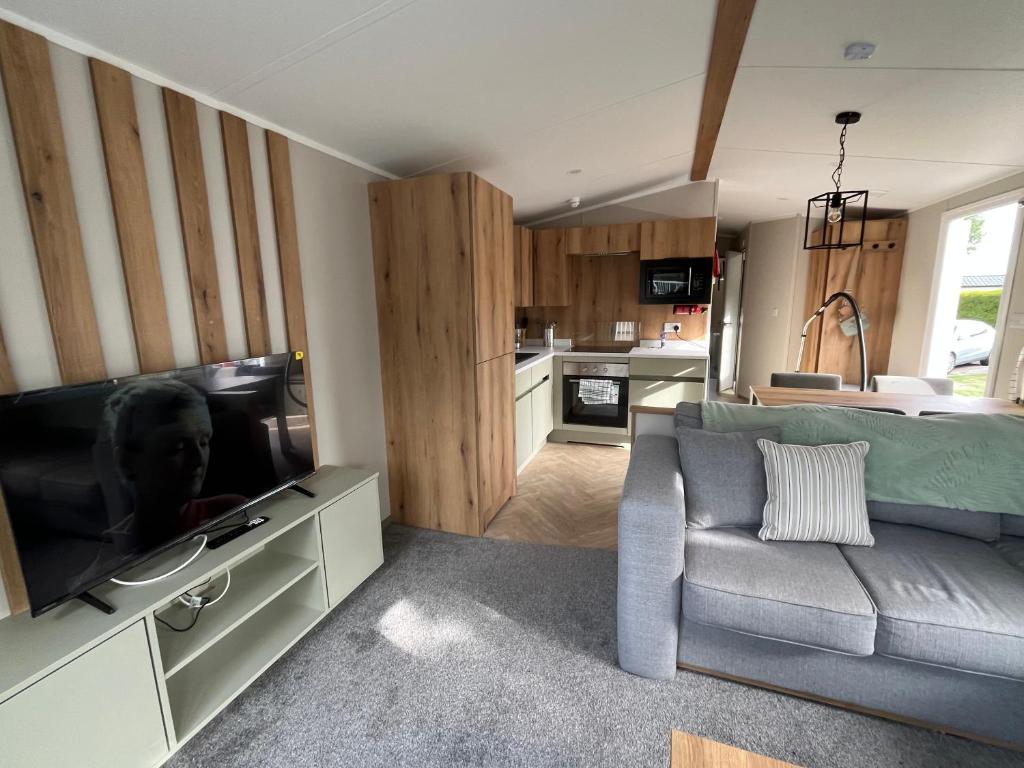 a living room with a couch and a flat screen tv at The Orchards modern caravan in Saint Osyth