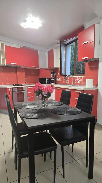 a kitchen with red cabinets and a black table and chairs at Terrace & Comfort Residence- SELF CHECK-IN in Bucharest