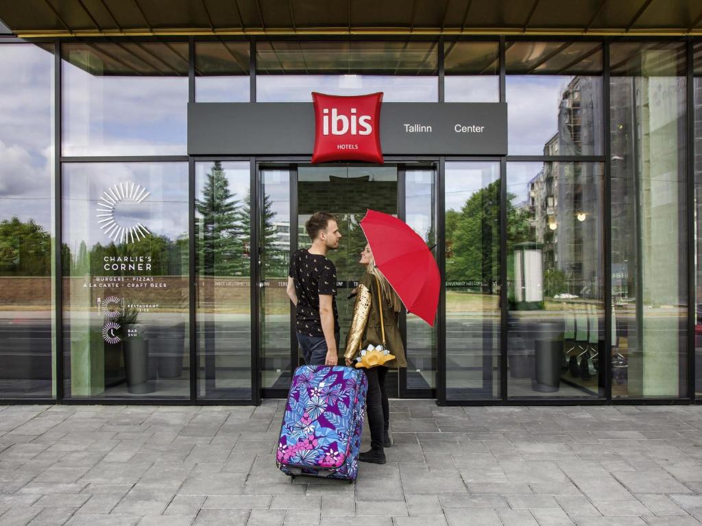 a woman with a red umbrella and a woman with a suitcase at ibis Tallinn Center in Tallinn