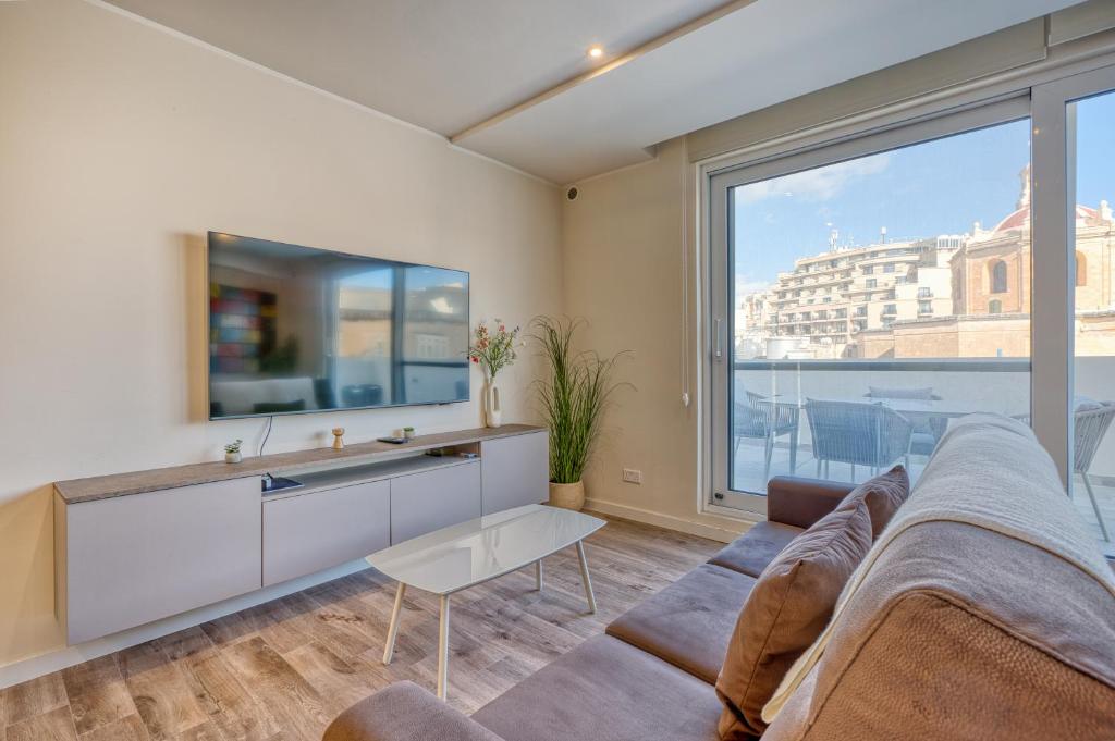 Una sala de estar con un sofá y una ventana grande. en Stella Maris - 'Star of the Sea' Penthouse-Sliema, en Sliema