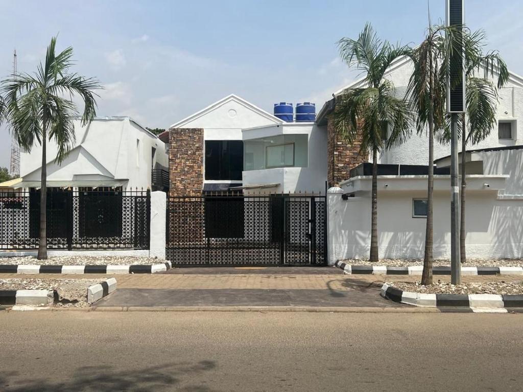 a white house with a fence and palm trees at Xplora in Abuja