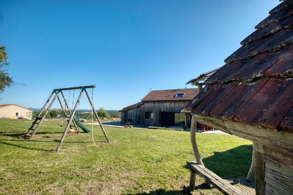 une vieille balançoire dans un champ à côté d'un bâtiment dans l'établissement L’Ancien Séchoir de Brantôme, à Puy-de-Fourches