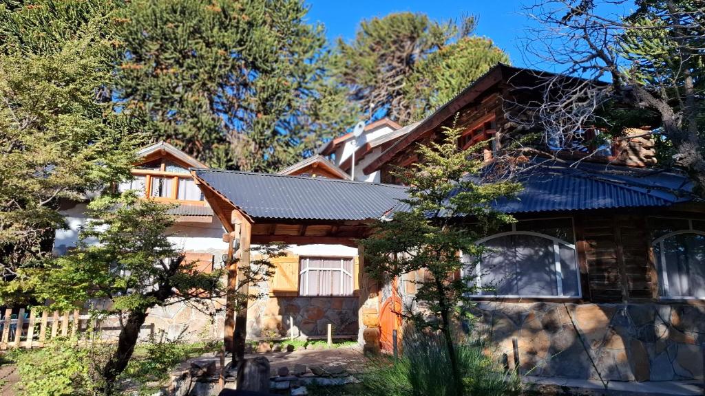 une maison avec un toit noir et des arbres dans l'établissement Alojamientos Titin, à Villa Pehuenia