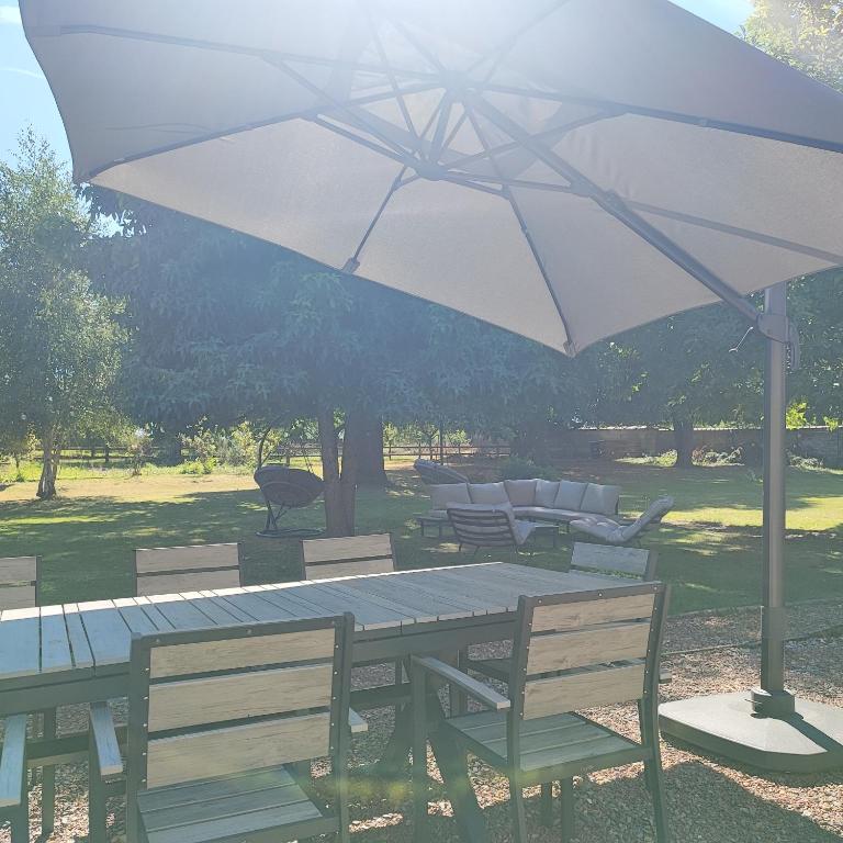 a table and chairs with an umbrella over it at Au Coeur du Verger in Thiescourt