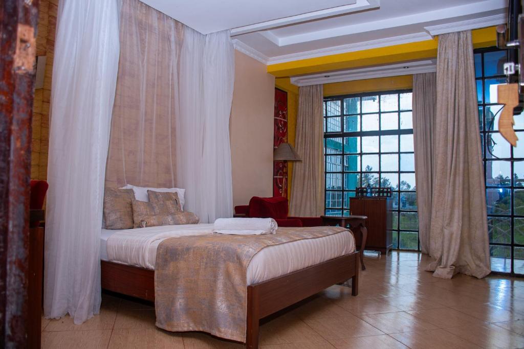 a bedroom with a bed and a large window at Hotel Quill in Busia